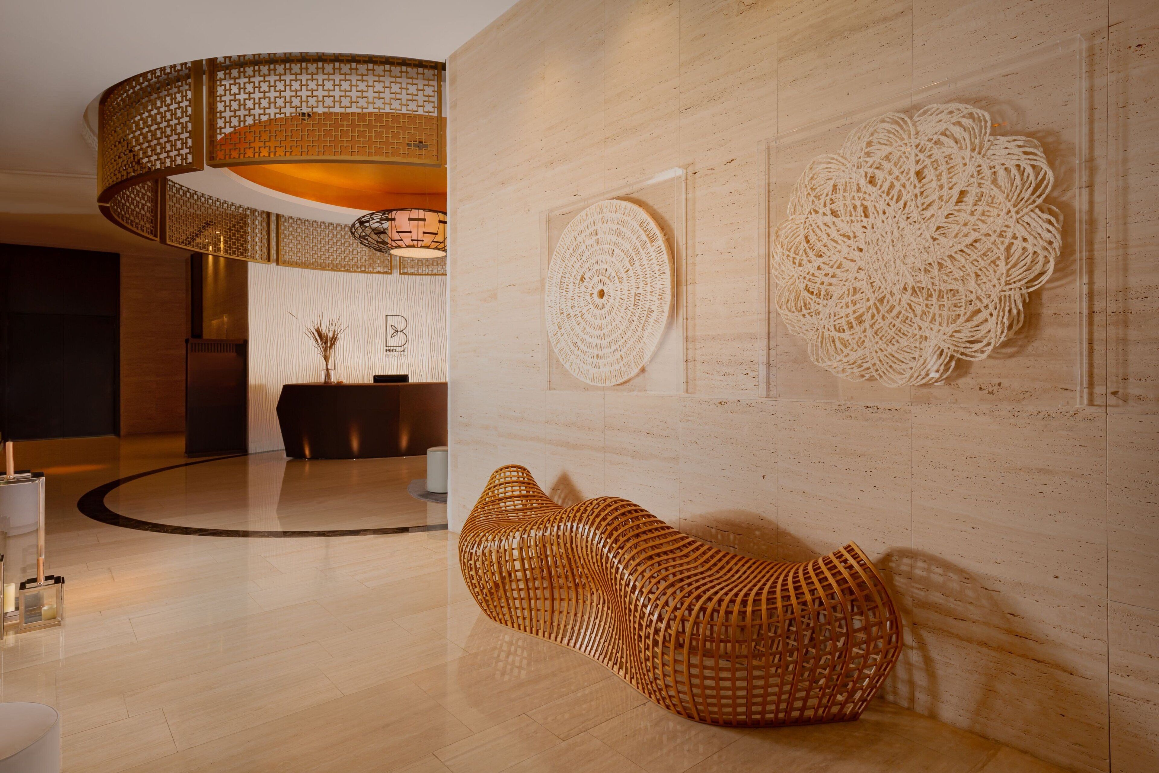 Eine moderne Lobby mit einer runden Holzkonstruktion, einer gewobenen Bank und dekorativer Wandkunst.