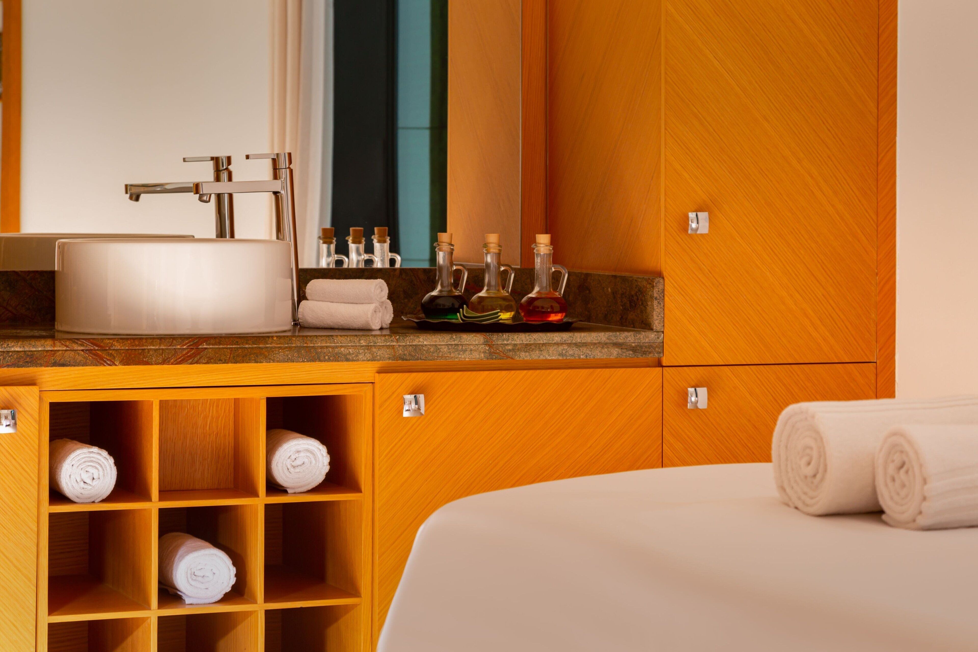 A hotel bathroom with a sink, mirror, and shelves with toiletries.