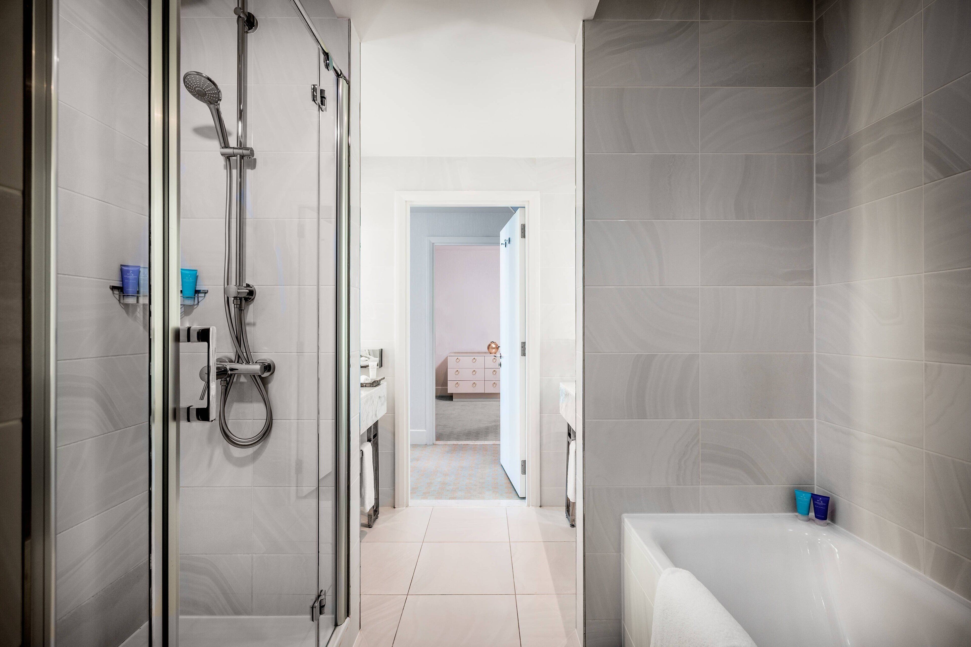 A modern bathroom with a glass shower enclosure, a bathtub, and a vanity with a mirror.