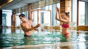 Um homem e uma mulher em uma piscina, com água espirrando ao redor.