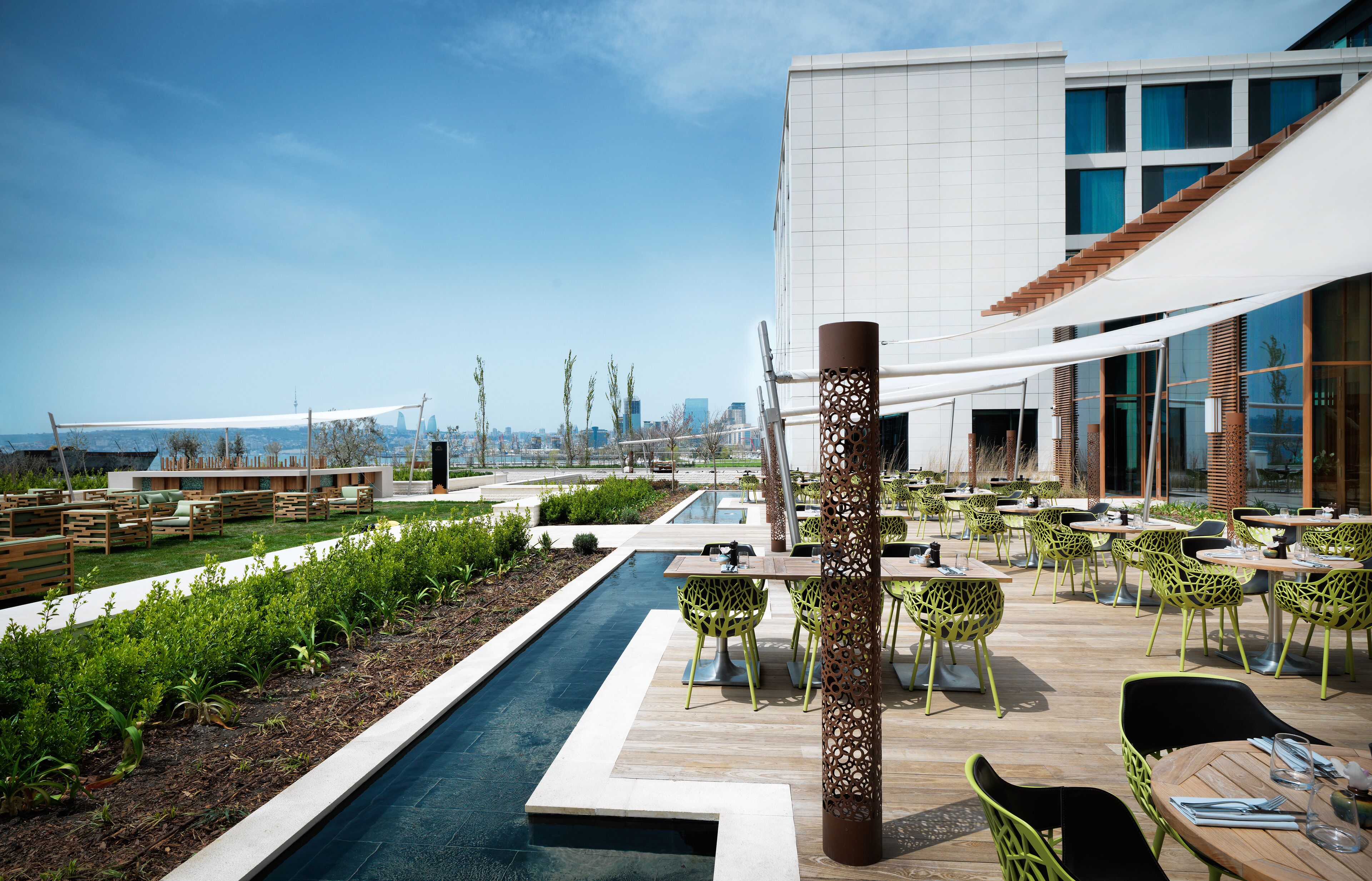 A rooftop patio with a pool, outdoor seating, and a city view.