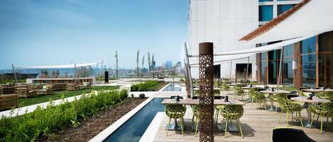 A rooftop patio with a pool, outdoor seating, and a city view.