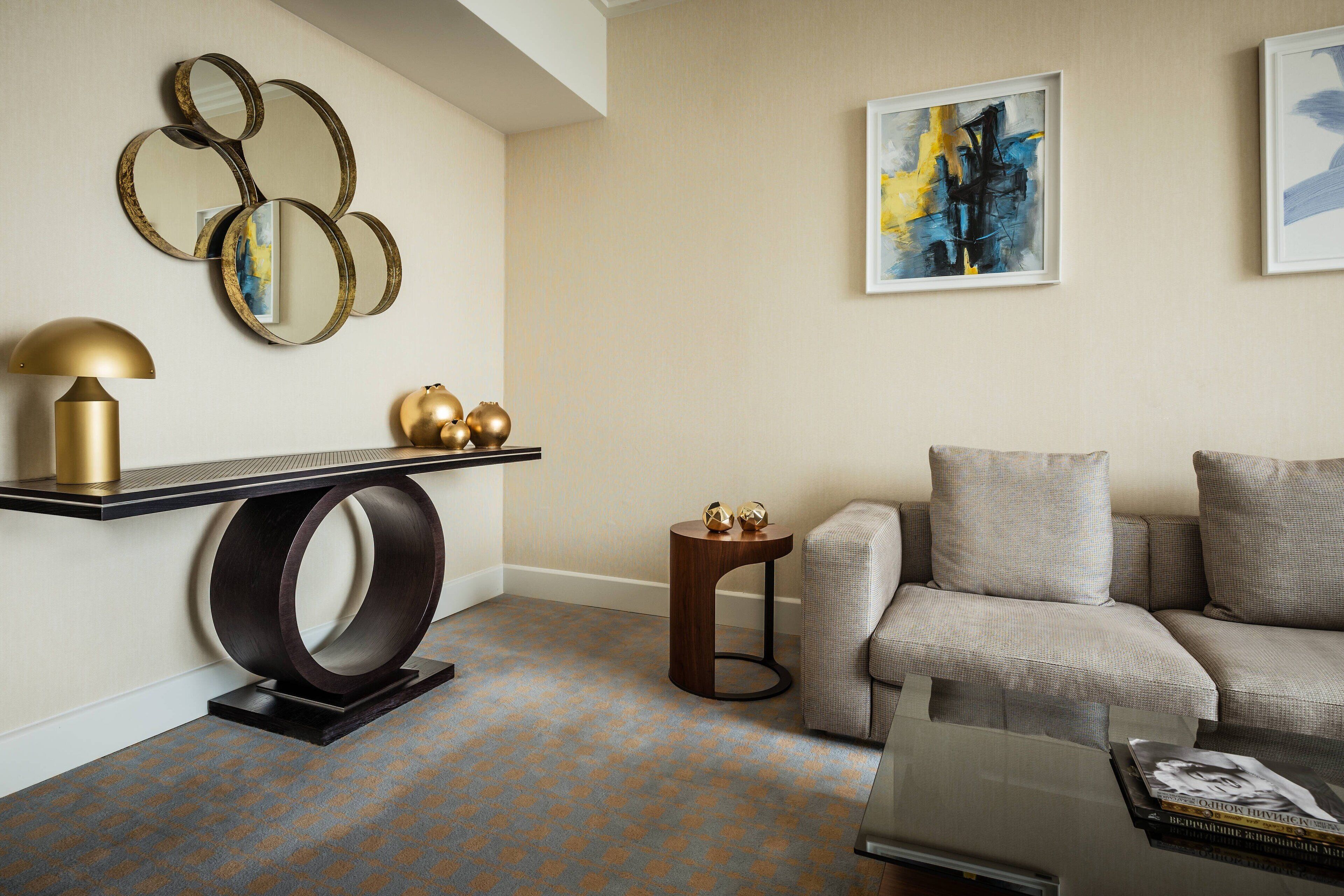 A modern living room with a sofa, a coffee table, a side table with decorative items, a lamp, and wall art.