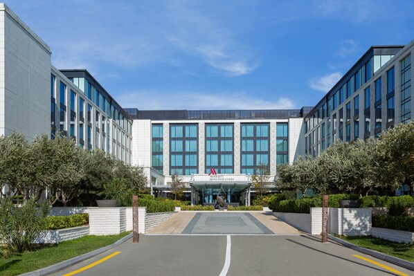 Un hôtel moderne doté d’une façade en verre, d’une entrée centrale et d’une allée aménagée.