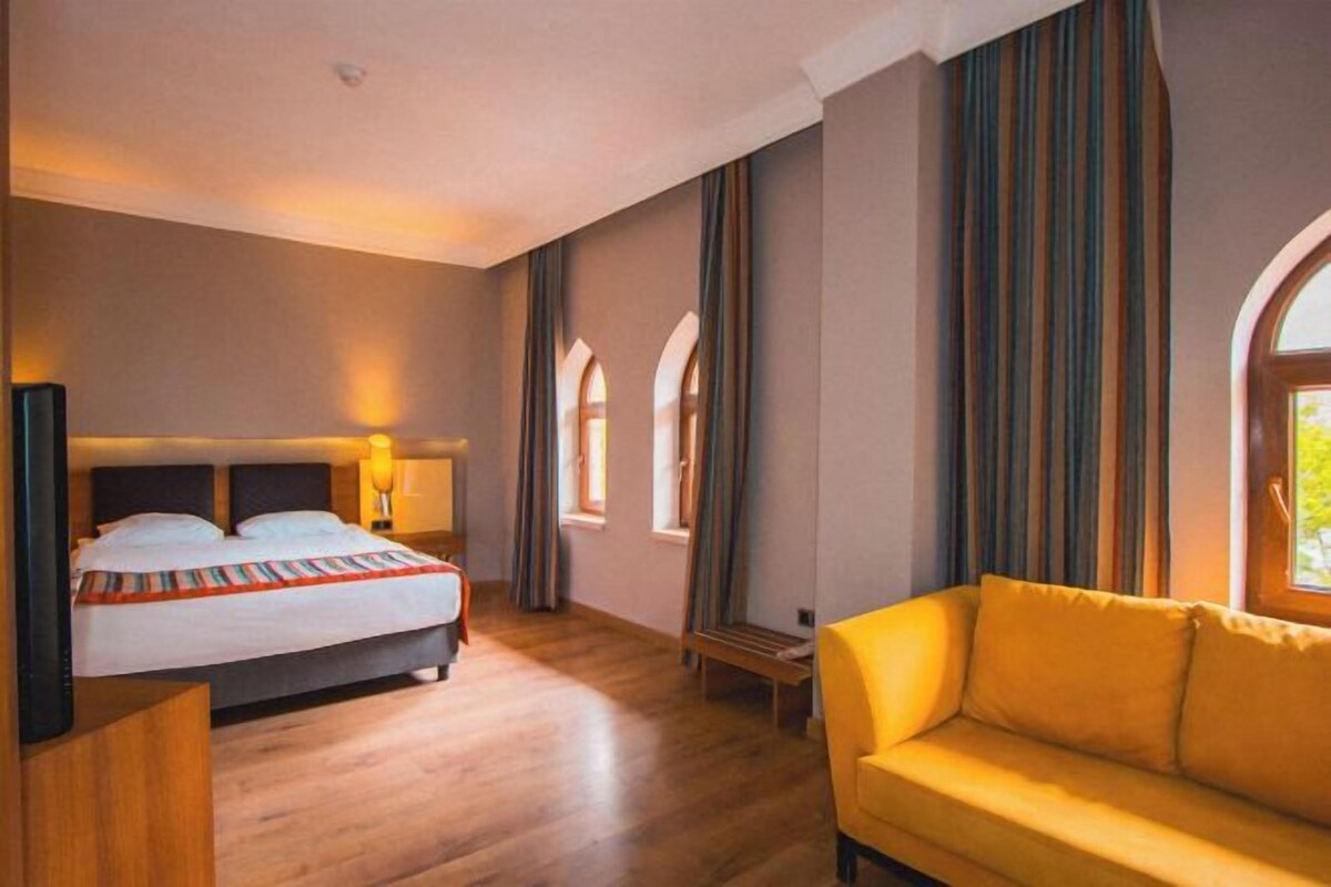 Et hotelværelse med seng, sofa og et vindue.
