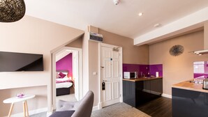 A modern hotel room with a flat-screen TV, a cozy seating area, a kitchenette, and a bathroom with a shower. - The Spires Serviced Apartments Edinburgh (Edinburgh)