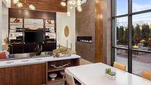 A modern kitchen with a built-in stove, a dining area with a white table, and a view of the outdoors through large windows. - Element by Marriott Bozeman (Bozeman)