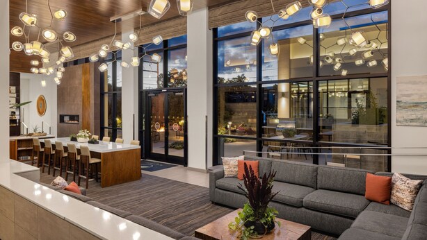 A modern hotel lobby with a central island dining area, a sofa with cushions, and a coffee table with plants. - Element by Marriott Bozeman (Bozeman)