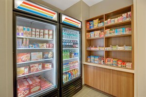 Un expositor refrigerado con diversos alimentos y un estante lleno de aperitivos.
