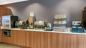 Zona de esmorzar a peu d'escala amb microones, torradora, cafetera i diversos recipients d'alimentació.