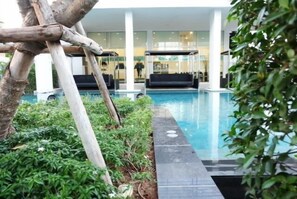 A modern indoor pool area with a glass barrier, surrounded by lush greenery and a minimalist architectural design. - Baan Kukiang at Hua Hin (Hua Hin)