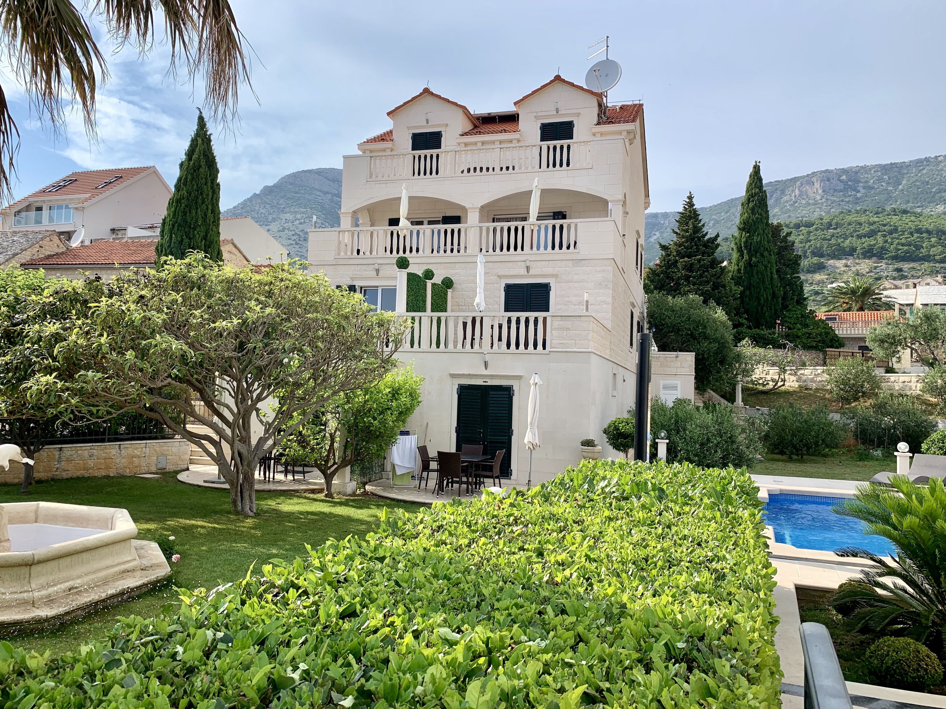 Um edifício de vários andares com piscina, cercado por vegetação e montanhas.