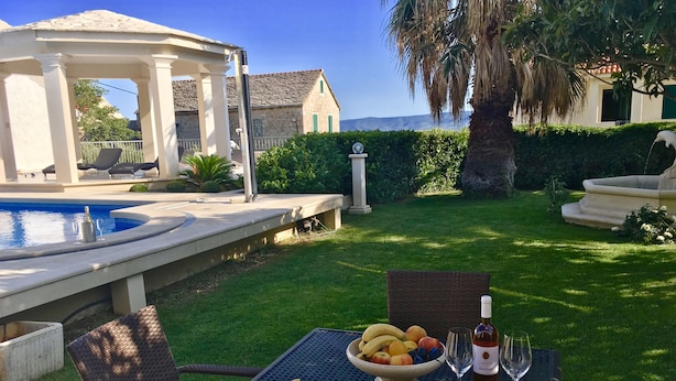 A patio with a table set for a meal, a pool, and a view of the sea. - Apartments Villa Jadranka - Adults Only (Bol)