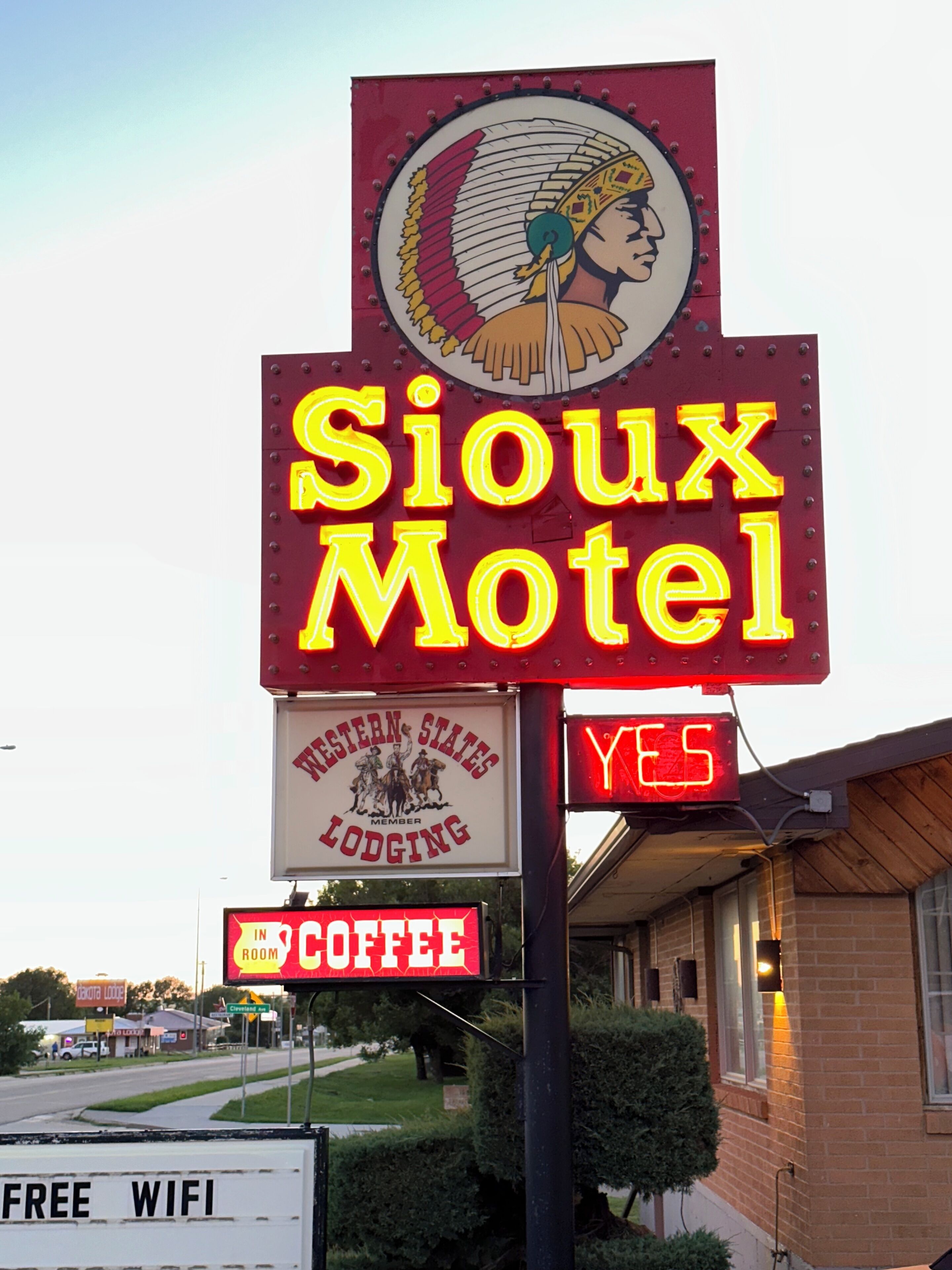 A motel sign with neon lights, a logo, and a 'Yes' sign indicating availability.