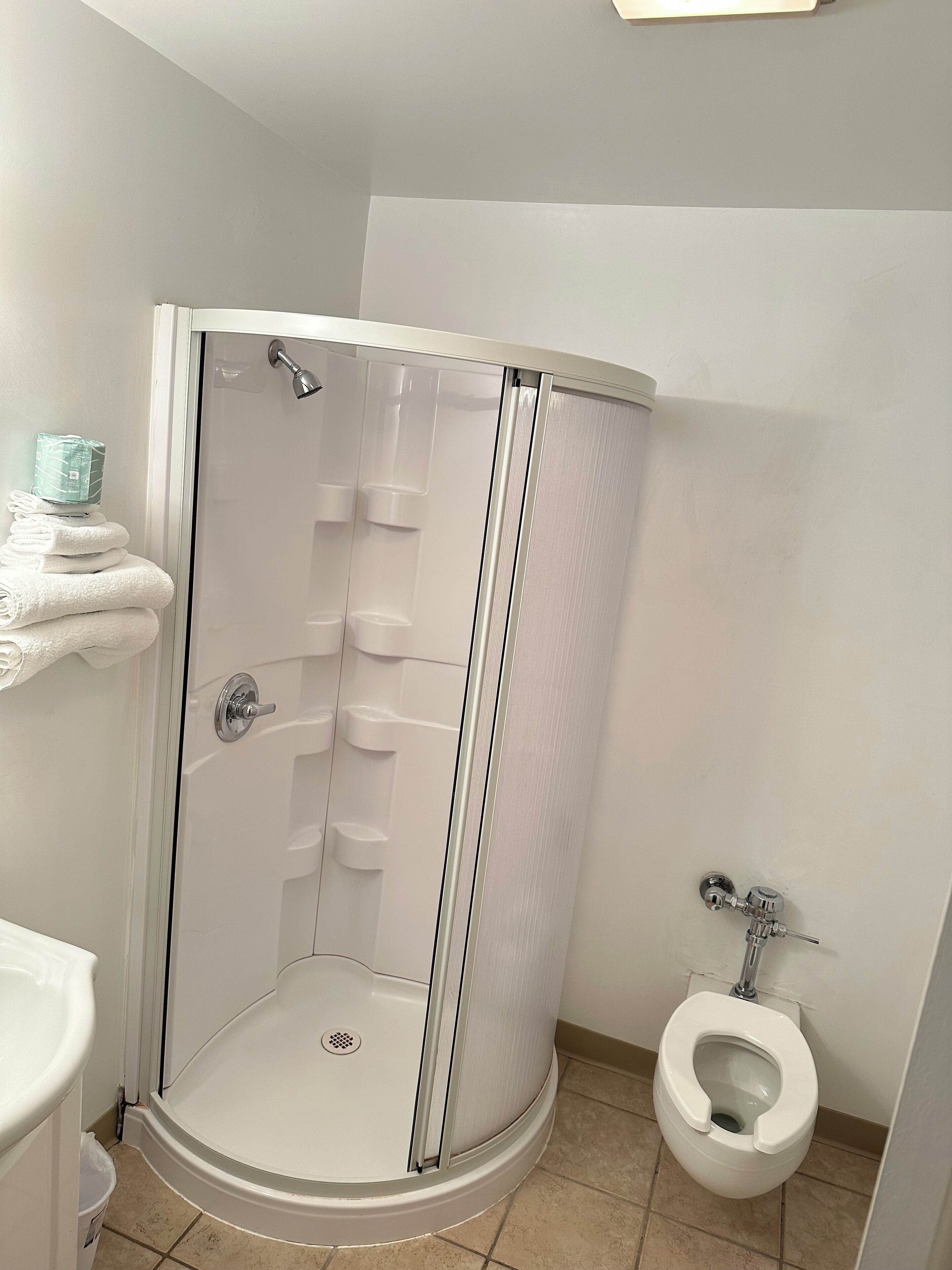 Un bagno con doccia, WC e asciugamani impilati.