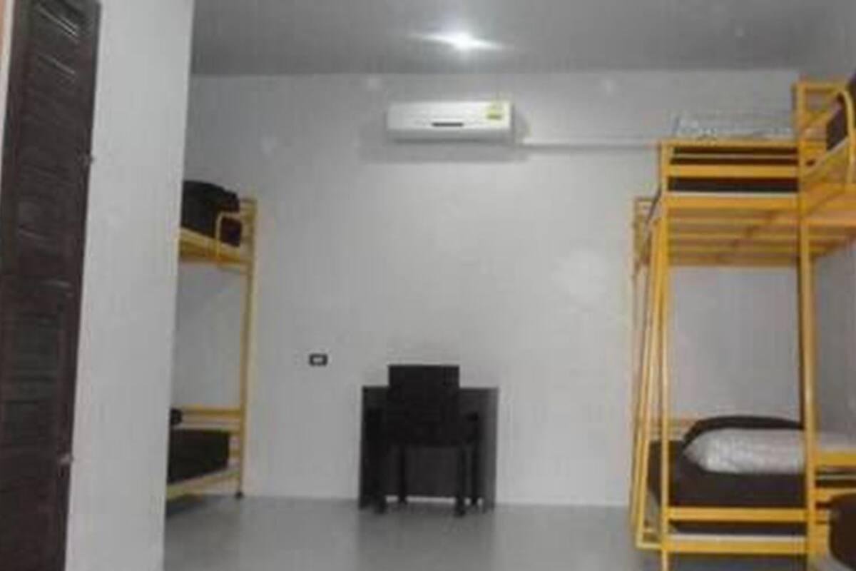 Un dormitorio con literas, un escritorio y un aire acondicionado.
