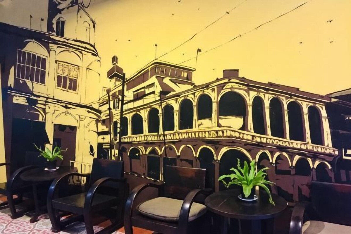 Un patio con fachada de edificio, mobiliario exterior y plantas en macetas.