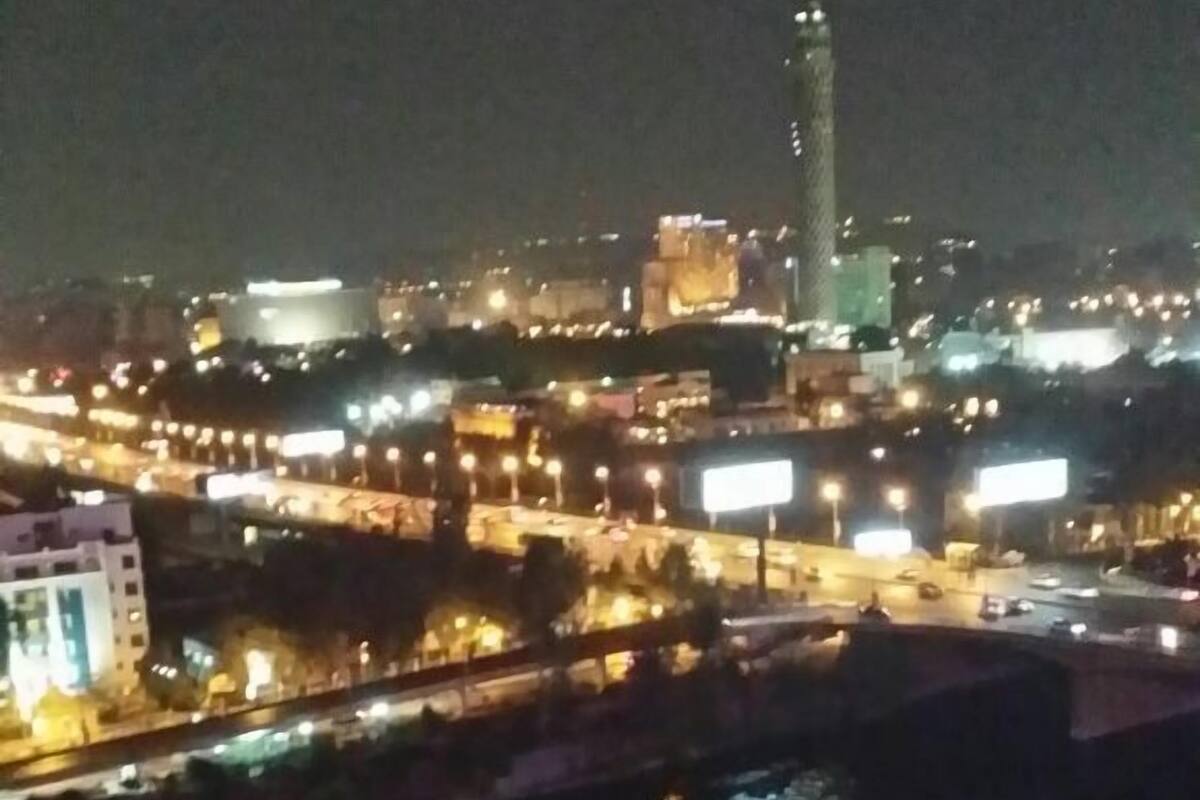 A nighttime cityscape with a river, illuminated buildings, and a prominent tower.