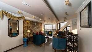 A spacious living area with a stone wall, modern furniture, and a city view. - Nile Boutique hotel (Giza)