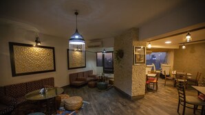 A modern interior with a round glass table, patterned sofas, and a brick accent wall. - Nile Boutique hotel (Giza)