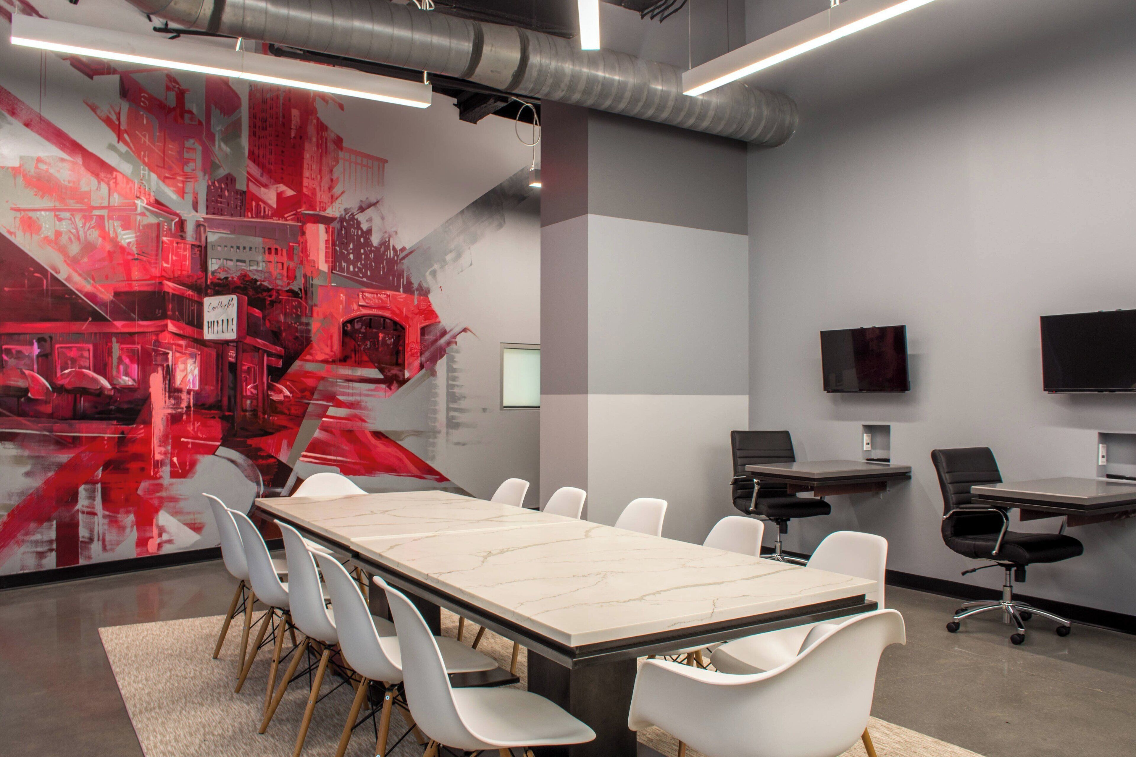 A conference room with a marble table, white chairs, a large abstract painting, and a flat-screen TV on the wall.
