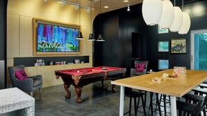 A modern lounge area with a pool table, seating, and a large artwork on the wall.