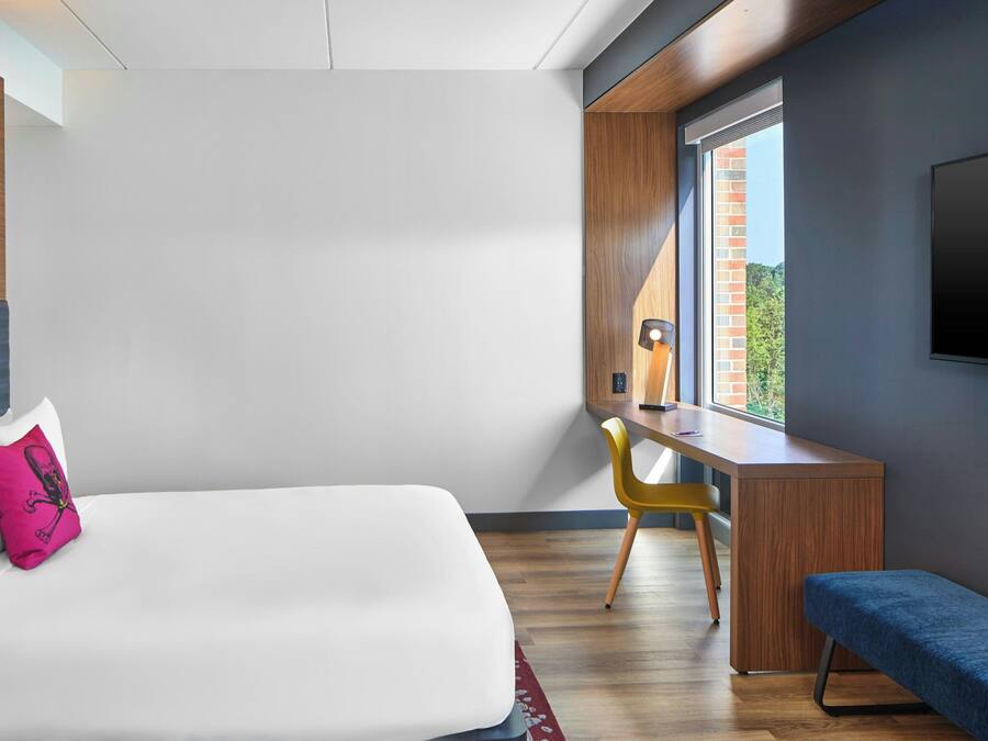 Una habitación de hotel moderna con una cama, un escritorio y un banco.