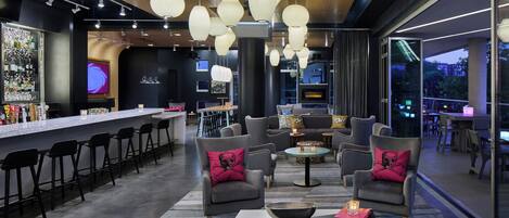 Un área de estar moderna con asientos de bar, sofás cómodos e iluminación colgante.