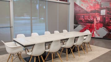 A conference room with a marble table and white chairs, large windows, and a cityscape mural.