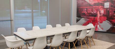 A conference room with a marble table and white chairs, large windows, and a cityscape mural.