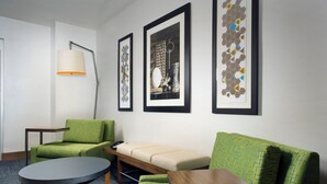 A modern hotel room with a green sofa, a round table, and three framed artworks on the wall. - Holiday Inn Express & Suites Bay City by IHG (Bay City)