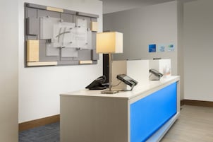 Mostrador de recepción de hotel con detalles azules, un teléfono, una lámpara y un letrero en la pared.