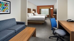 Ein Hotelzimmer mit Bett, Schreibtisch, Stuhl, Sofa und Fernseher.