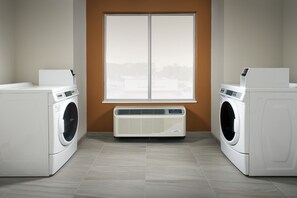 A laundry room with two front-loading washing machines and a wall-mounted dryer. - Holiday Inn Express & Suites Bay City by IHG (Bay City)