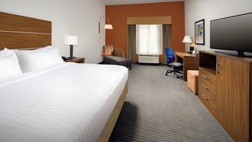 A hotel room with a large bed, a desk, a chair, a television, and a wardrobe.