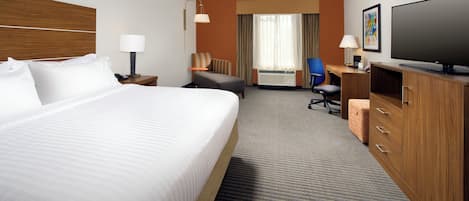 A hotel room with a large bed, a desk, a chair, a television, and a wardrobe.