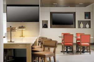 Un comedor moderno con una mesa blanca y sillas rojas, un televisor de pantalla plana montado en la pared y una lámpara sobre la mesa.
