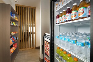 Habitación de hotel con un minibar repleto de aperitivos, bebidas y un refrigerador con diferentes opciones de refrescos.