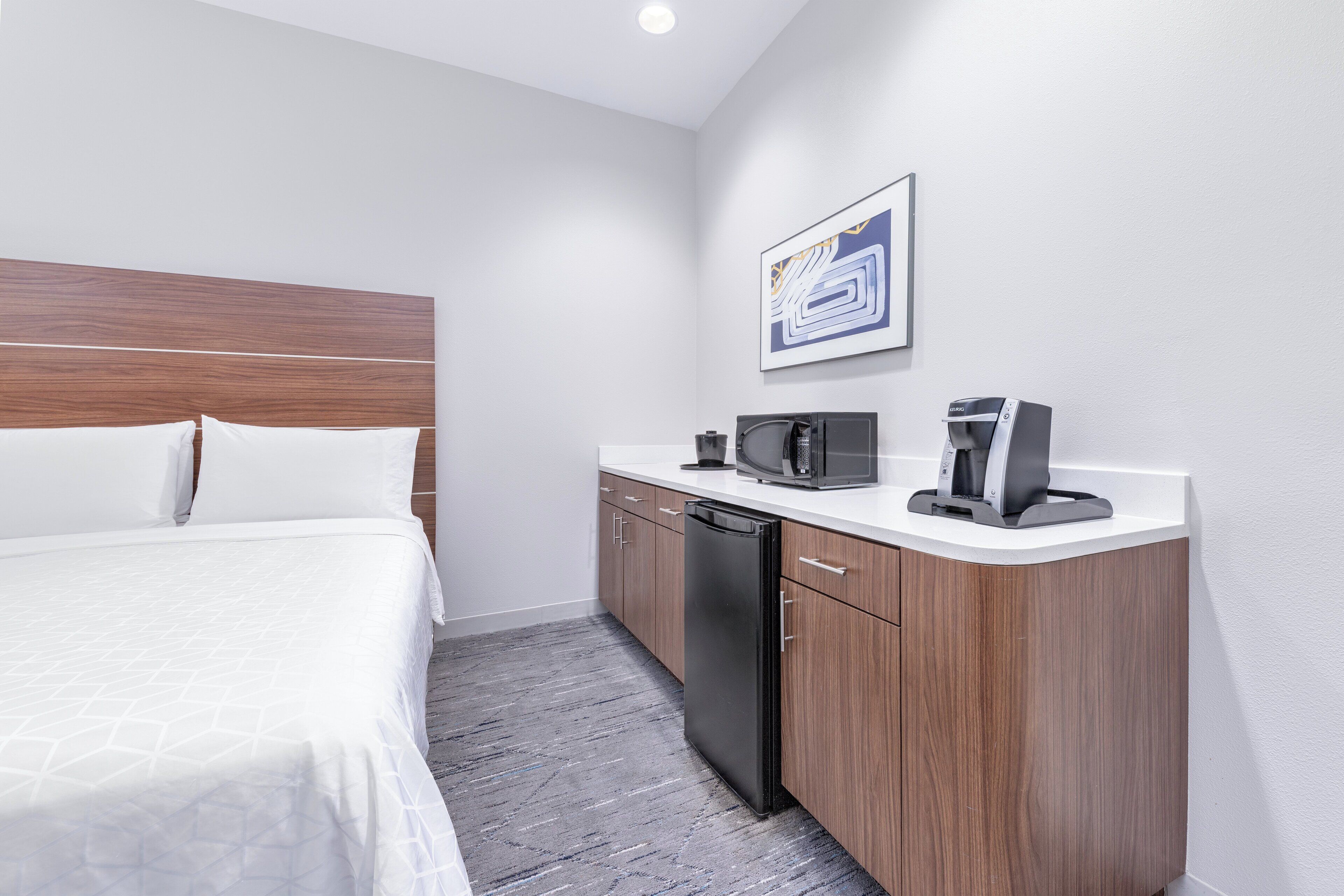 Een hotelkamer met een bed, een magnetron, een koffiezetapparaat en een vaatwasser.