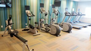 A gym with various cardio machines, a television mounted on the wall, and a patterned carpet. - Holiday Inn Express & Suites Pahrump by IHG (Pahrump)