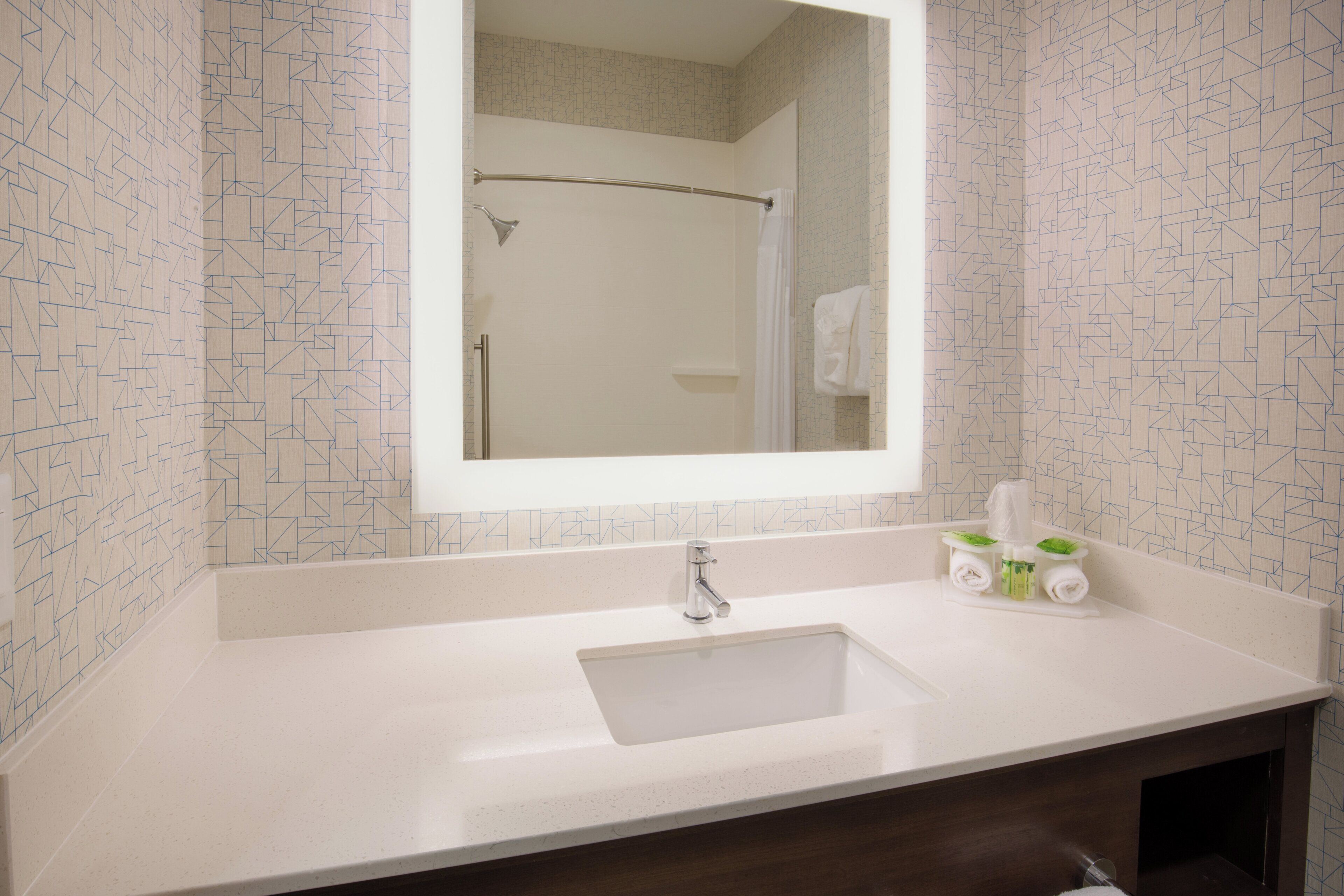 Un baño con lavamanos blanco, un espejo y un perchero para toallas.