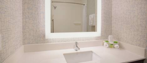 Un baño con lavamanos blanco, un espejo y un perchero para toallas.