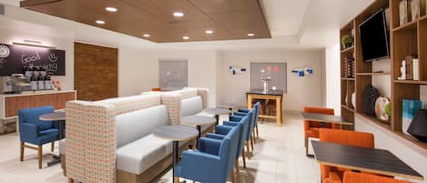 Un café moderno con zona de estar, mesas y televisor.