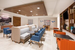 A modern cafe with a seating area, tables, and a television. - Holiday Inn Express & Suites Pahrump by IHG (Pahrump)