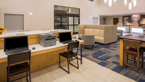 Un moderno vestíbulo de hotel con mostrador de recepción, computadoras y zonas de estar.