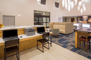 A modern hotel lobby with a reception desk, computers, and seating areas. - Holiday Inn Express & Suites Pahrump by IHG (Pahrump)