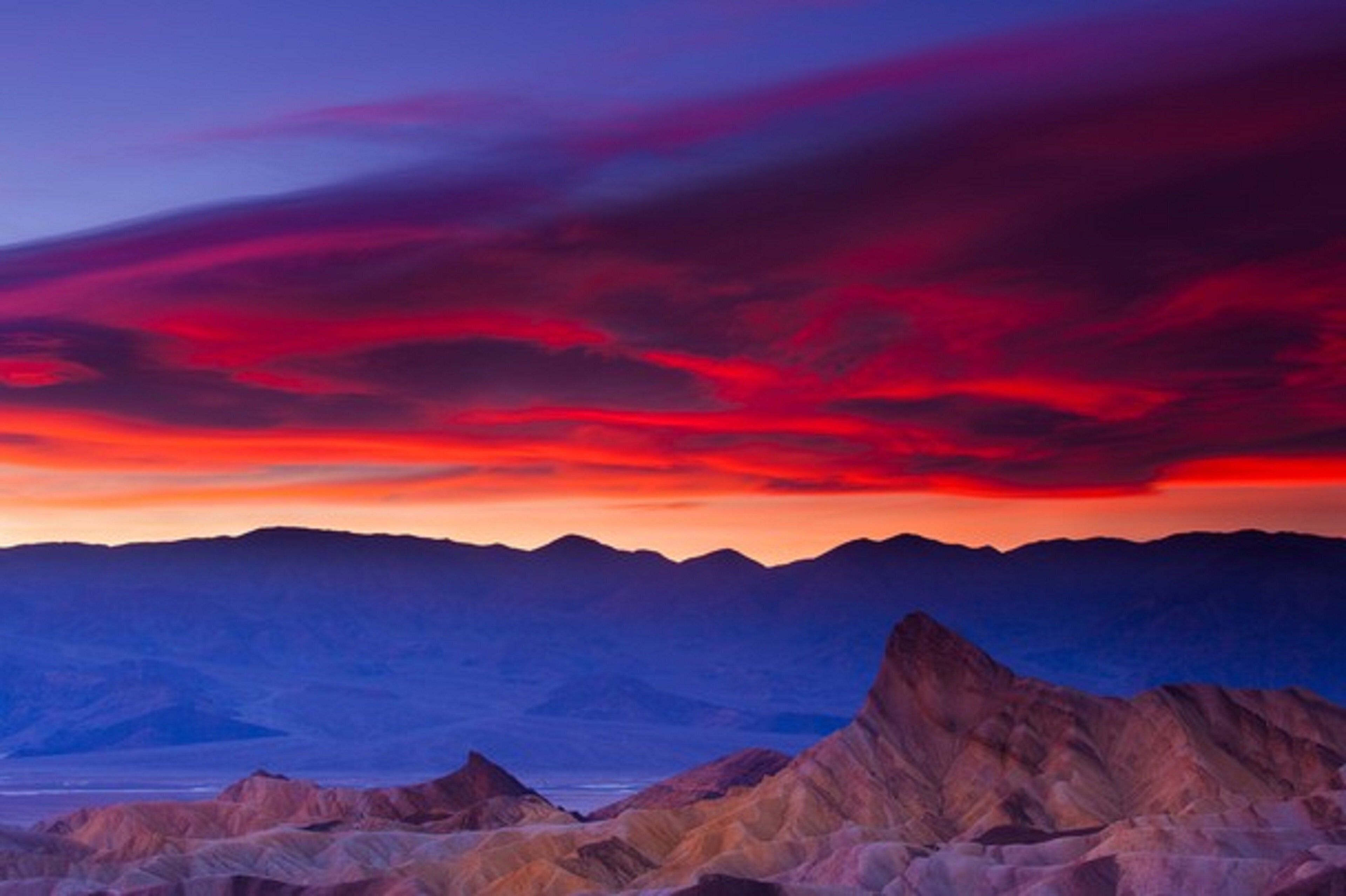A mountainous landscape with a sunset sky.