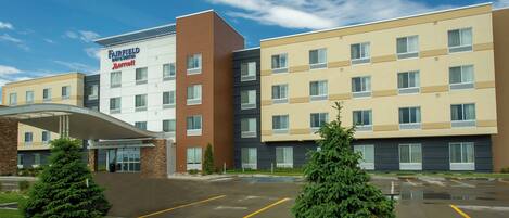 Un hotel Fairfield Inn & Suites by Marriott con un diseño moderno, que cuenta con una entrada cubierta y un estacionamiento.