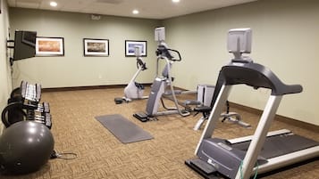 A fitness center with exercise equipment, including a treadmill, elliptical, and weights.
