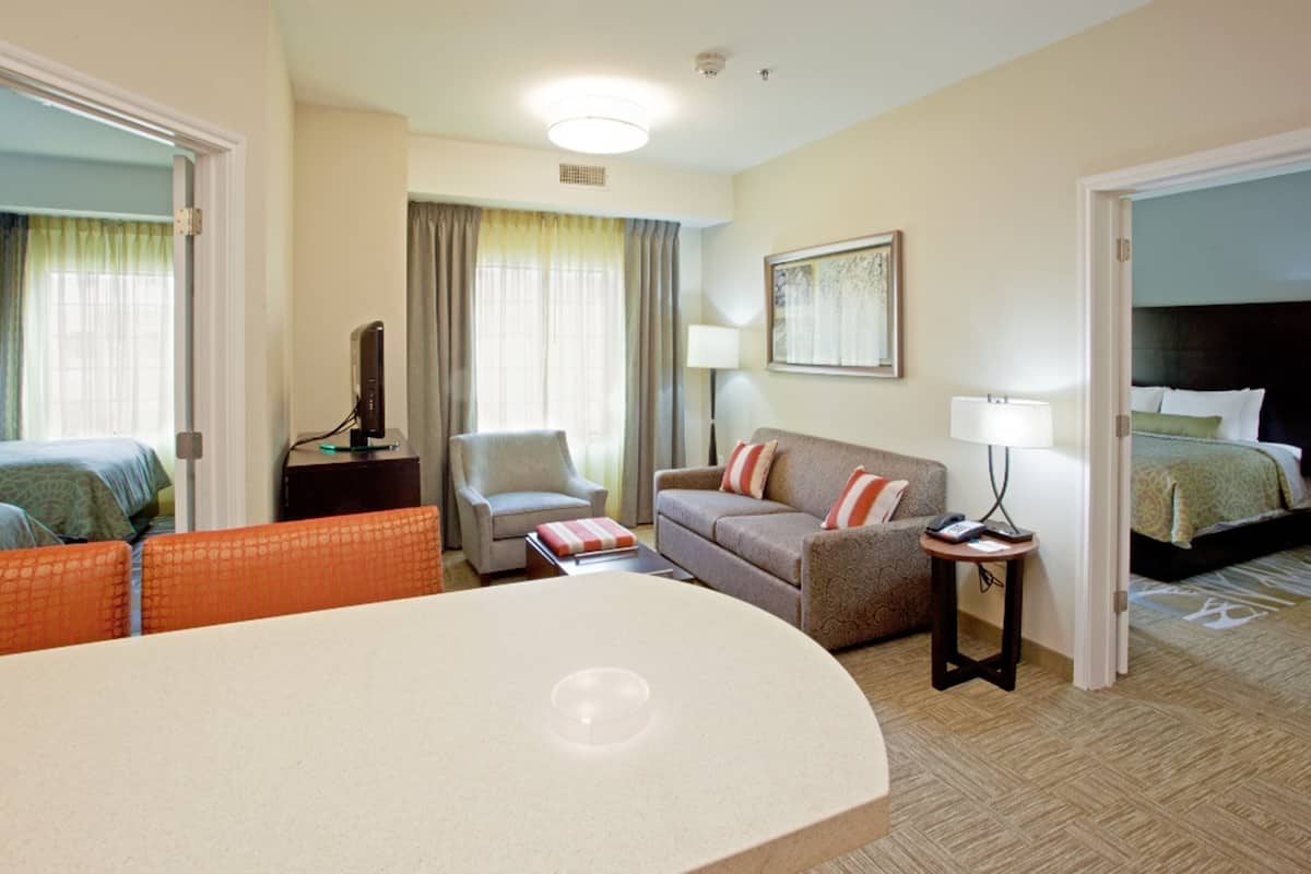 Hotelkamer met een bed, een bank, een stoel, een klein tafeltje en een bureau met een lamp.